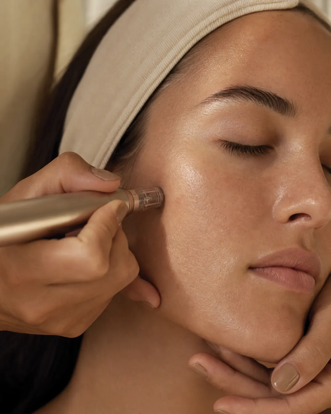 A therapist holding a micro-needling pen against a client’s cheek.